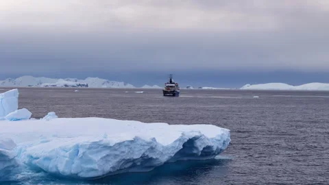 Expedition ship sailing past a massive iceberg in antarctica Stock Footage 320669497