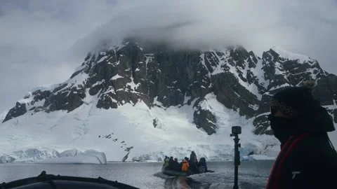 Expedition zodiac passes towering mountain in Antarctica Stock Footage 339096702