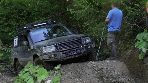 Expeditionary SUV trying overcom dangerous complex terrain at forest via winch. Stock Footage 76728209