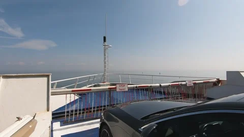 A expensive car parked on the deck of a ferry as it sails across calm waters Stock Footage 290064939