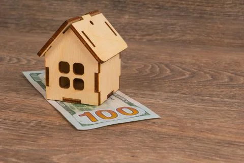 Expensive utilities cost concept with wooden house model and 100 dollar bankn Stock Photos