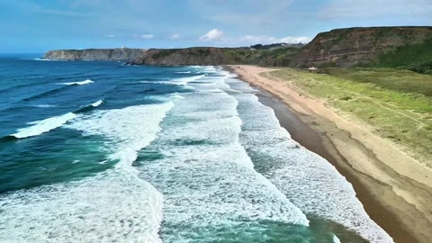 Experience breathtaking coastal views with waves crashing on a sandy beach, a Stock Footage 311216572