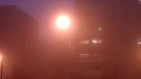 Experience a captivating night as fog envelops the streets, with illuminated lig Stock Footage 297199775