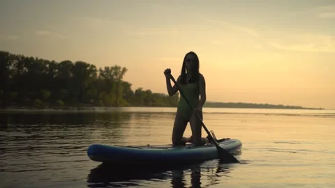 Experience the joy of paddleboarding during a stunning sunset on a serene and Video stock 282725890