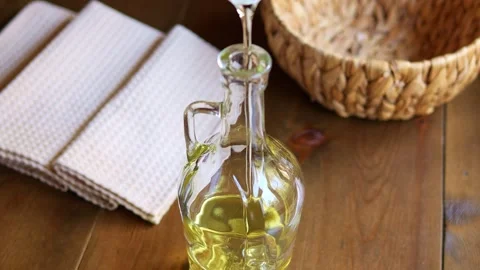 Experience mesmerizing sight of plant based oil slowly pouring into glass bottle Stock Footage 267963256