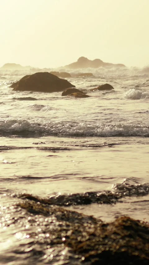 Experience the serene ocean waves crashing against the rocky shoreline at Stock Footage 305982185