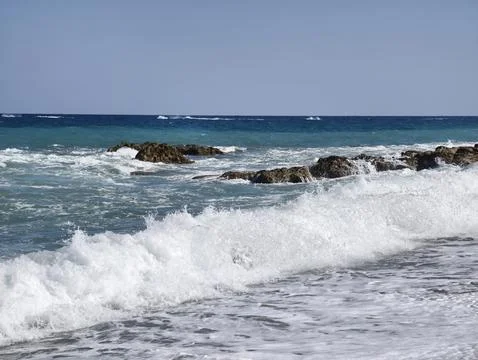 Experience the serene ocean waves gracefully crashing on the beautiful rock.. Photos