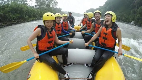 Experience the thrill of whitewater rafting as two dynamic Asian girls expertly Stock Footage 128436965