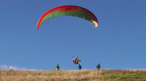 Experience the thrilling moment of a tandem paragliding landing and wing Stockbeeldmateriaal 59211248