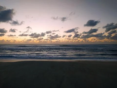 Experience the tranquility of a coastal sunrise. This dramatic beach scene fe Stock Photos