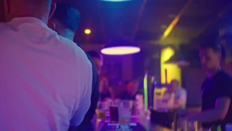 Experience a vibrant nightlife scene at a lively bar filled with colorful Stock Footage 316540053