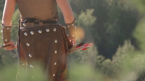 Experienced archer is aiming in green forest sunny day. Man in national leather Stock Footage 82371262