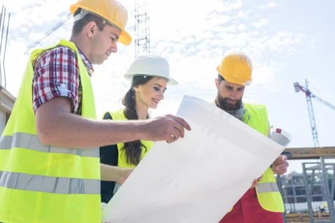 Experienced architect analyzing a blueprint on the construction site Stock Photos