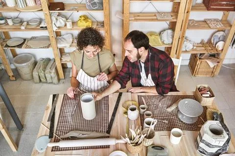An experienced artisan guides an apprentice in ceramic techniques, sharing Fotos Stock