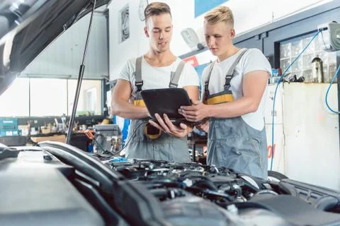 Experienced auto mechanic using a laptop for scanning engine errors Foto stock