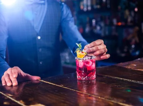 Experienced barkeeper formulates a cocktail while standing near the bar counter Stock Photos