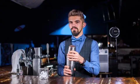Experienced barman demonstrates the process of making a cocktail while standing Stock Photos