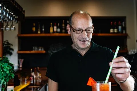 Experienced bartender shaking a cocktail with a straw. Preparing a cocktail in a Stock Photos