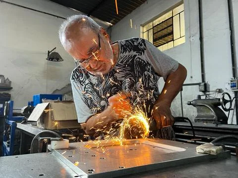 Experienced blacksmith man in a garage working to Stock Photos