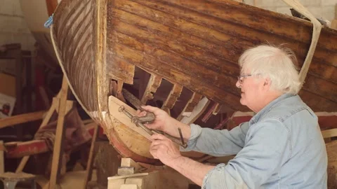 Experienced boat builder clamping hull plank wooden boat repair Stock Footage 338159238