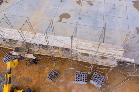 An experienced bricklayer stands on scaffolding to construct a working concrete Stock Photos