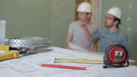Experienced builders discussing plan repair standing indoors. They hold in hands Stock Footage 79334338