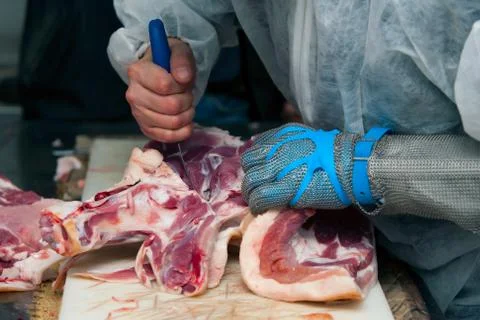 Experienced butcher using protective gloves to expertly cut and prepare fresh Foto stock