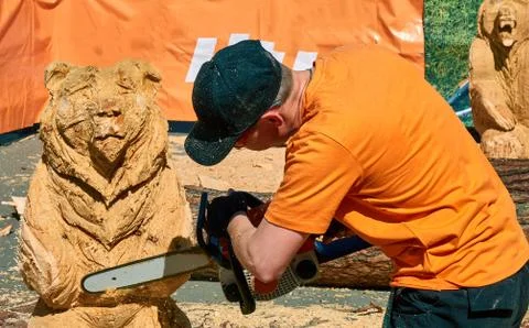 Experienced carpenter making a big wooden bear sculpture with a chainsaw Stock Photos
