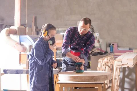 Experienced carpenter teaching young apprentice at workshop Stock Photos