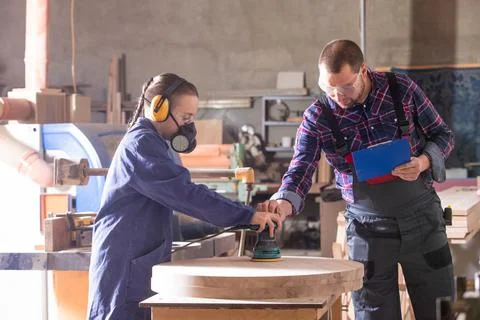 Experienced carpenter teaching young apprentice at workshop 库存照片