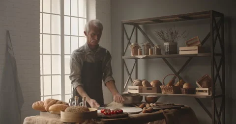 Experienced caucasian elderly man is starting to make pizza, applying flour to Video stock 133123013