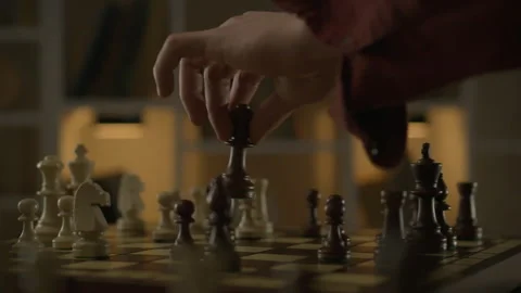 An experienced chess player confidently moves a piece on the board, creating Stock Footage 263829564