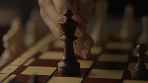 An experienced chess player is pleased to knock over the king piece, ending Stock Footage 276574459