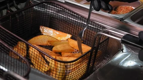 Experienced cook adding spices to pan-fried potatoes. Stockbeeldmateriaal 267294799