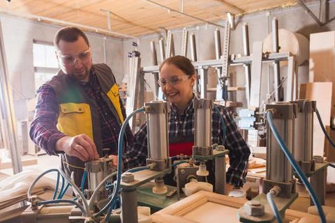 Experienced craftsman teaching female apprentice to work with woodworking Stock Photos