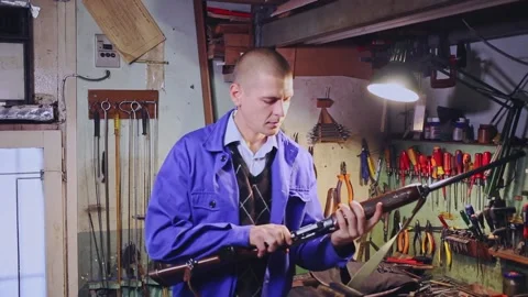 Experienced craftsman of weapons workshop inspecting semi-automatic hunting Stock Footage 158914423