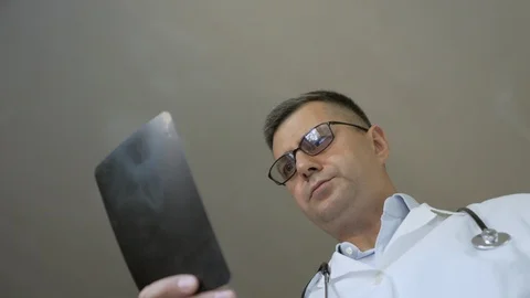 An experienced doctor looking at x-rays of the patient's foot. Stock Footage 112424087