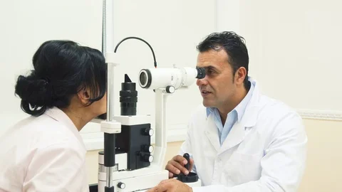 An experienced doctor looks at the device for testing the patients vision Stock Footage 80998453