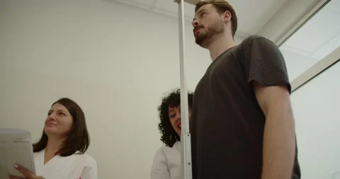 Experienced doctor measuring height of young patient with stadiometer in Stock Footage 258370531