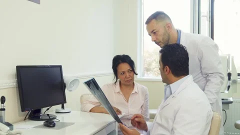 Experienced doctors discuss X-Ray results with a concerned patient Stock Footage 311992382