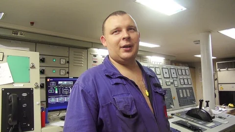 Experienced engineer in blue uniform talks standing by panel 動画素材 116609084