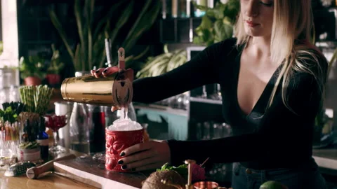 Experienced female bartender using a strainer and pouring drink over tiki glass Stock Footage 199461550