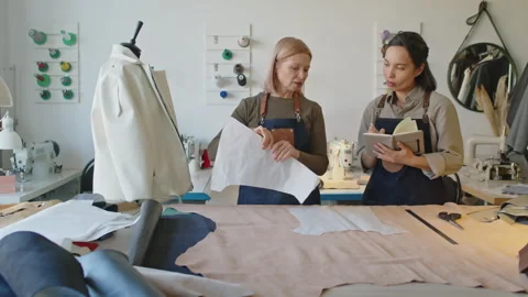 Experienced Female Tailor Teaching Young Apprentice in Workshop Video stock 244683045