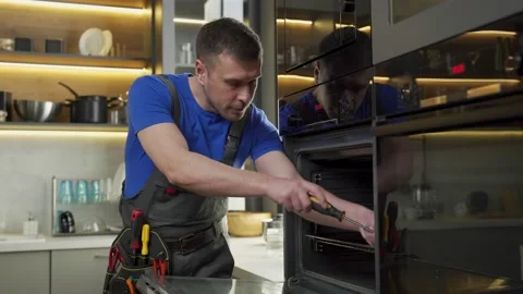 Experienced foreman fixes oven using screwdriver in kitchen Stock Footage 170364298