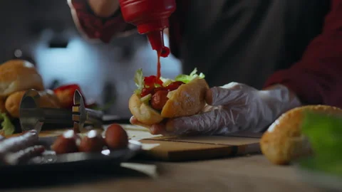 An experienced hot dog master adds ketchup to a hot dog carefully placed in Stock Footage 271145857