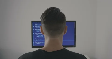Experienced IT programmer works on a new program. Young man hacker writes the Stock Footage 95733021