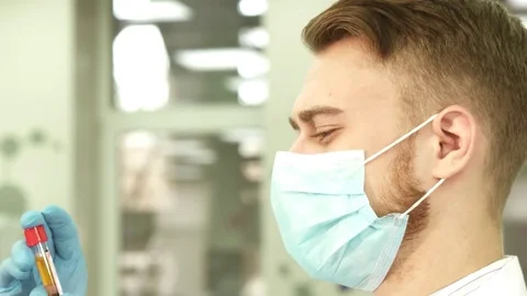 An experienced laboratory assistant carefully examines a test tube with blood Stock Footage 84862720