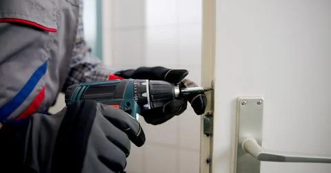 The Experienced Locksmith Expertly Replacing A Damaged Door Lock. Stock Photos