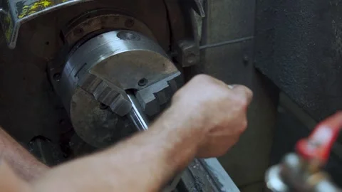 Experienced machinist manually threading metal part on a lathe machine Stock Footage 306179735