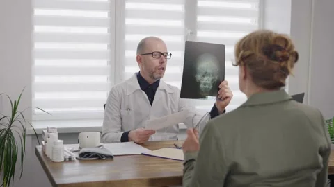 An experienced male doctor describes an x-ray of an elderly woman. Stock Footage